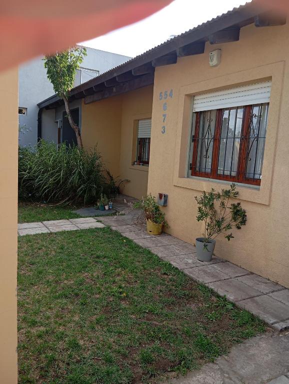 a yellow house with two potted plants in front of it at lo de Jor in Quequén