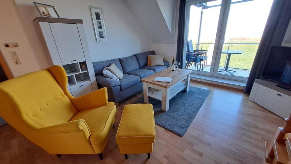 a living room with a blue couch and a yellow chair at Residenz am Deich NDD 28 in Norden