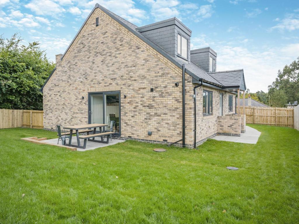 a brick house with a picnic table in a yard at The Caddy's Lodge - Uk47762 in Bamburgh