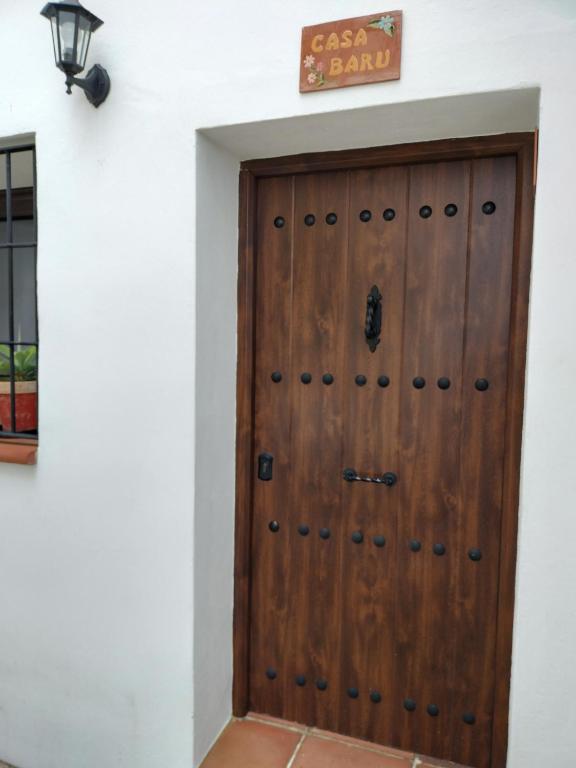 a wooden door in a white wall with a sign above it at Casa Rural "Baru" in Alpandeire