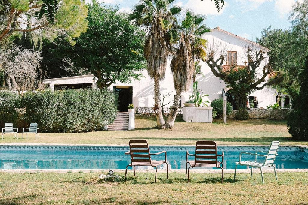 three chairs sitting in front of a swimming pool at Masia Can Pares in Sant Pere de Ribes