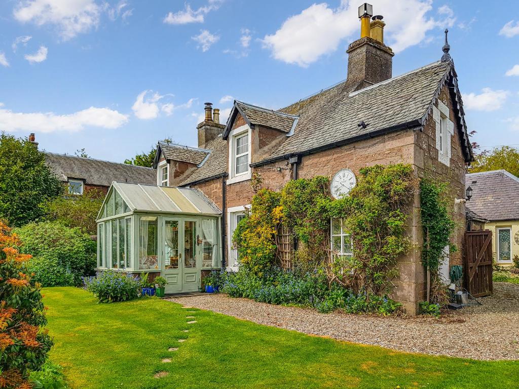 an old brick house with a conservatory in a yard at Ivy Cottage in Crieff