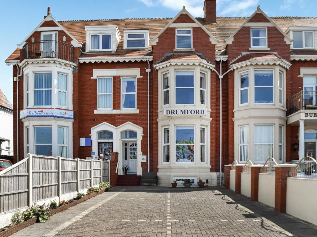 a brick house with a white fence in front of it at Drumford in Blackpool