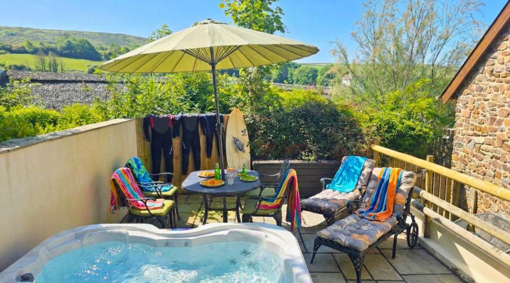 a patio with a table and chairs and an umbrella at CROYDE THATCHERS HIDEAWAY 2 Bedrooms in Croyde