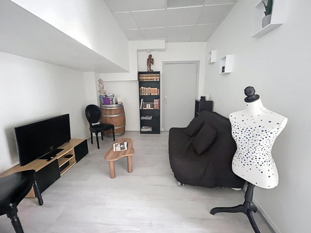a living room with a chair and a television at Le Antoine in Compiègne