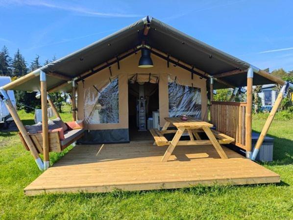 a tent with a wooden deck in the grass at Luxe safaritent in Leersum