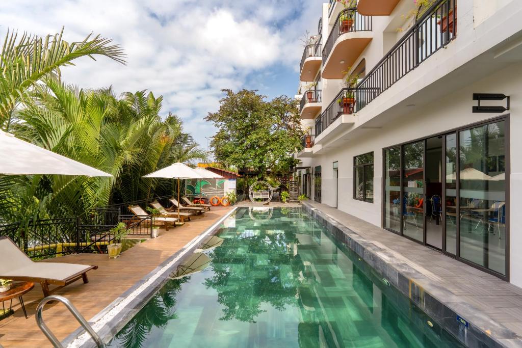 a pool at a hotel with chairs and umbrellas at Muoi Villa in Hiếu Nhơn