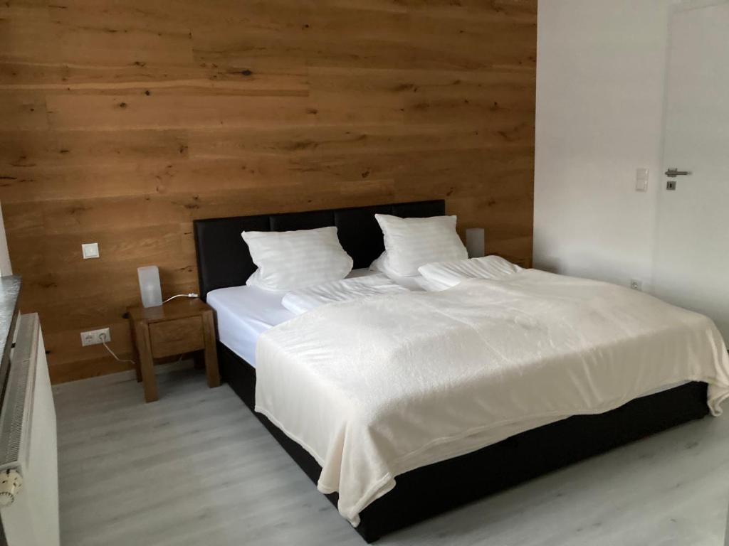 a bedroom with a white bed with a wooden wall at Ferienwohnung Hammerbergblick Rittersgrün in Breitenbrunn
