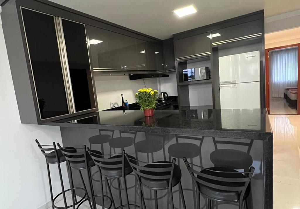 a kitchen with black cabinets and stools at a counter at Apartamento em Pomerode - 205 in Pomerode