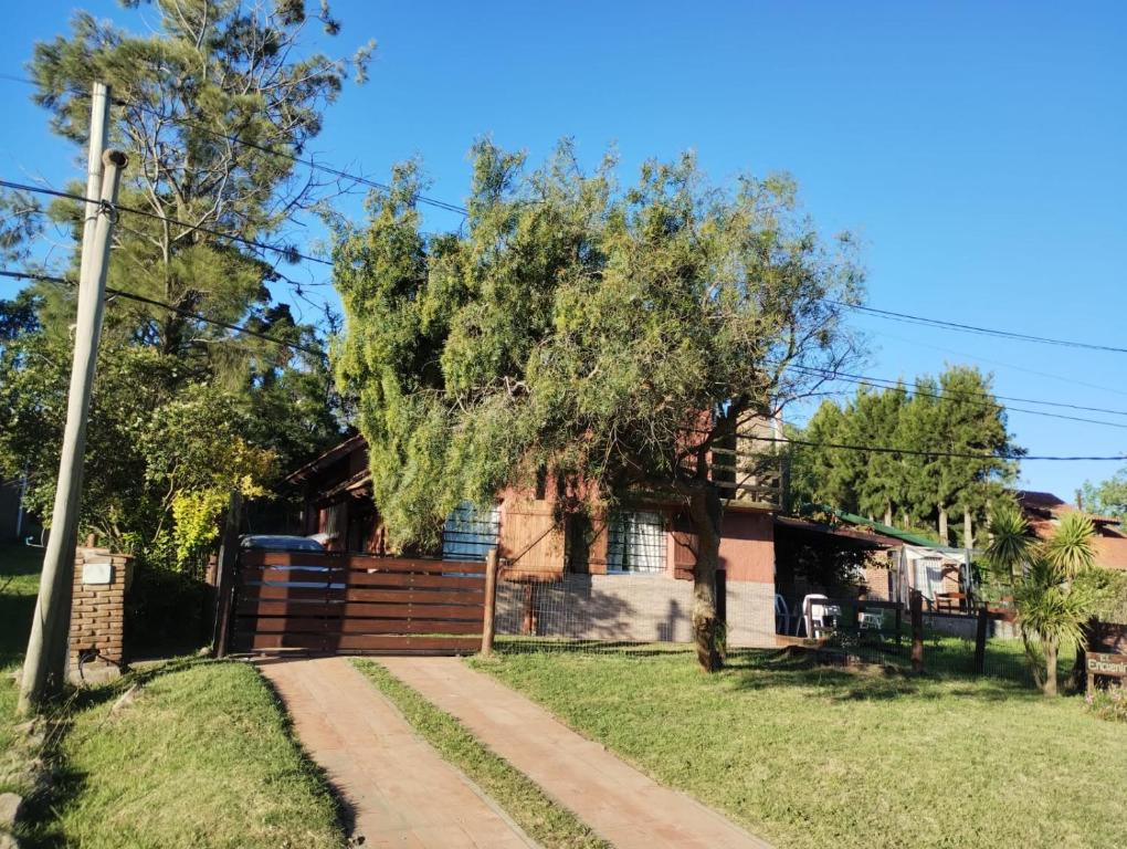 a house with a fence and a tree at El Encuentro in Piriápolis