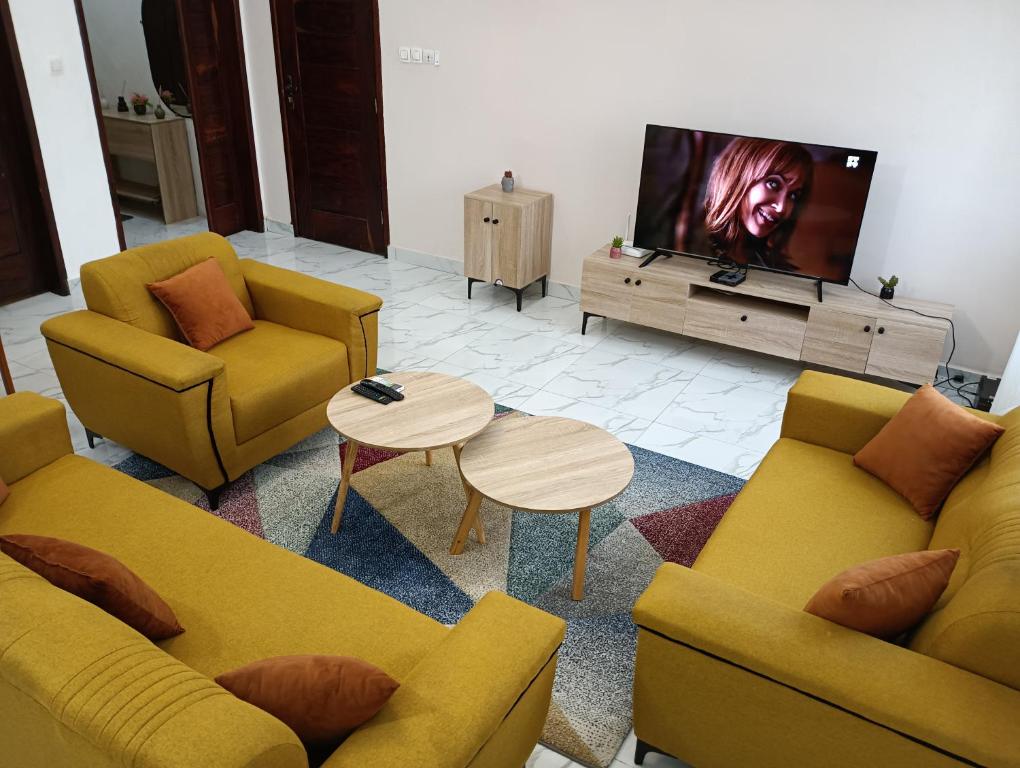 un soggiorno con due divani e una TV a schermo piatto di Chez Yenou a Cotonou