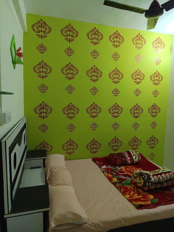 a bedroom with a green wall with a bed at Swami Inn Lodging in Trimbak
