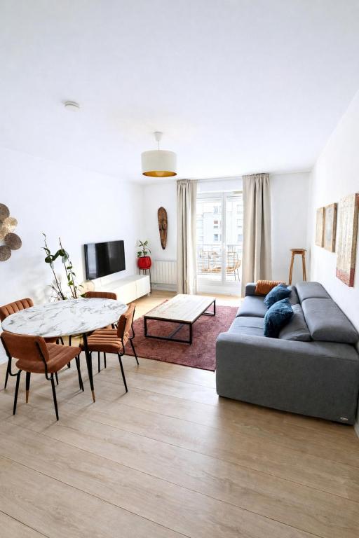 a living room with a couch and a table at Charme et Douceur By UTA HOUSE in Saint-Denis