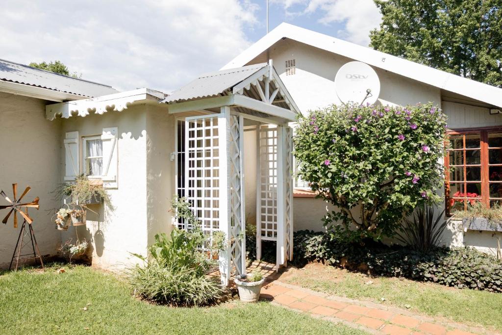 a white house with a gate in the yard at Douglas Drift Cottages in Underberg