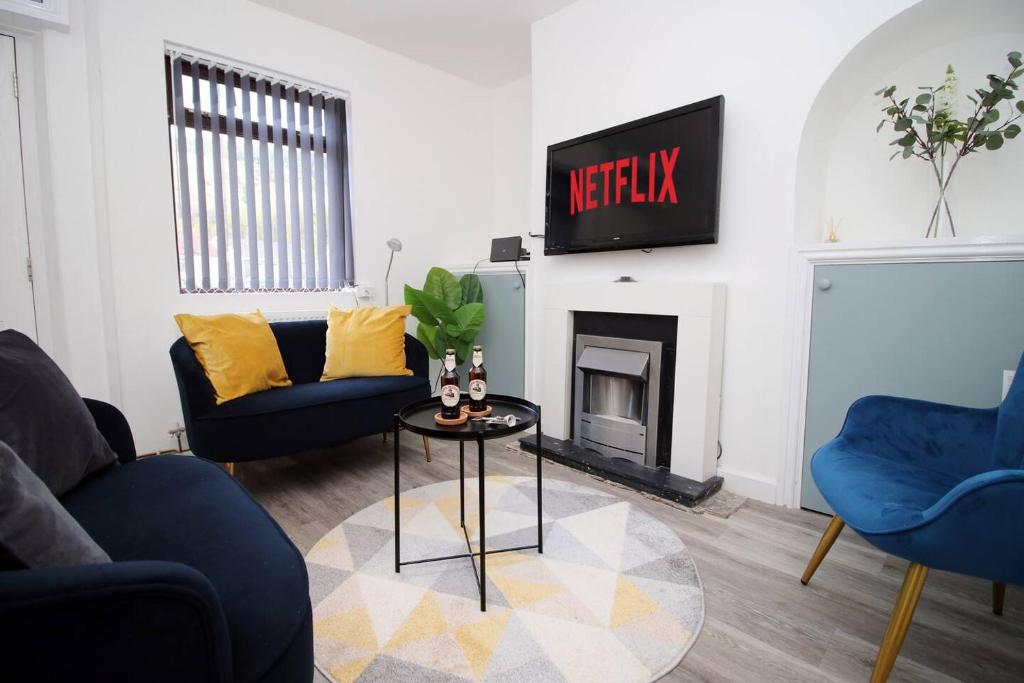 a living room with two blue chairs and a fireplace at Afan House by STAE-Homes in Glyncorrwg