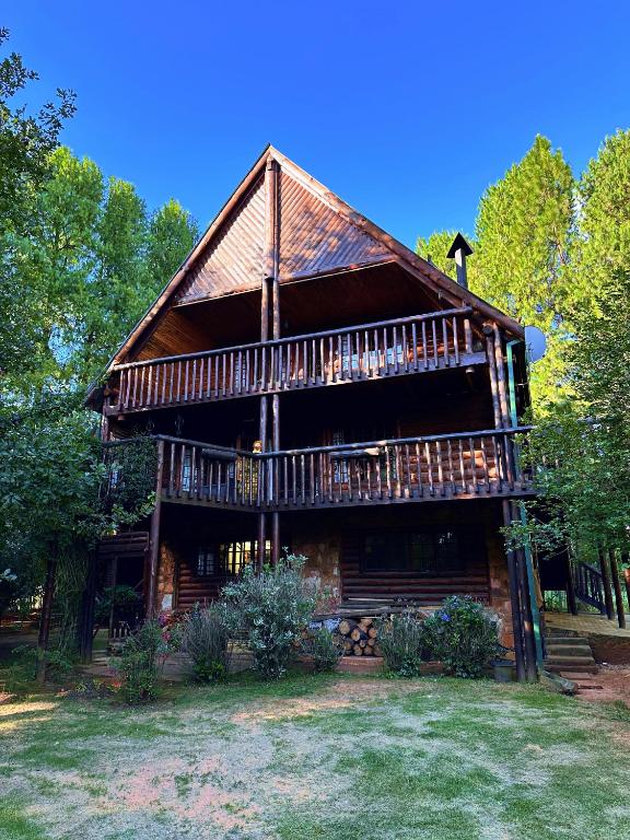 a large log cabin with a deck and trees at Little Lions in Dullstroom