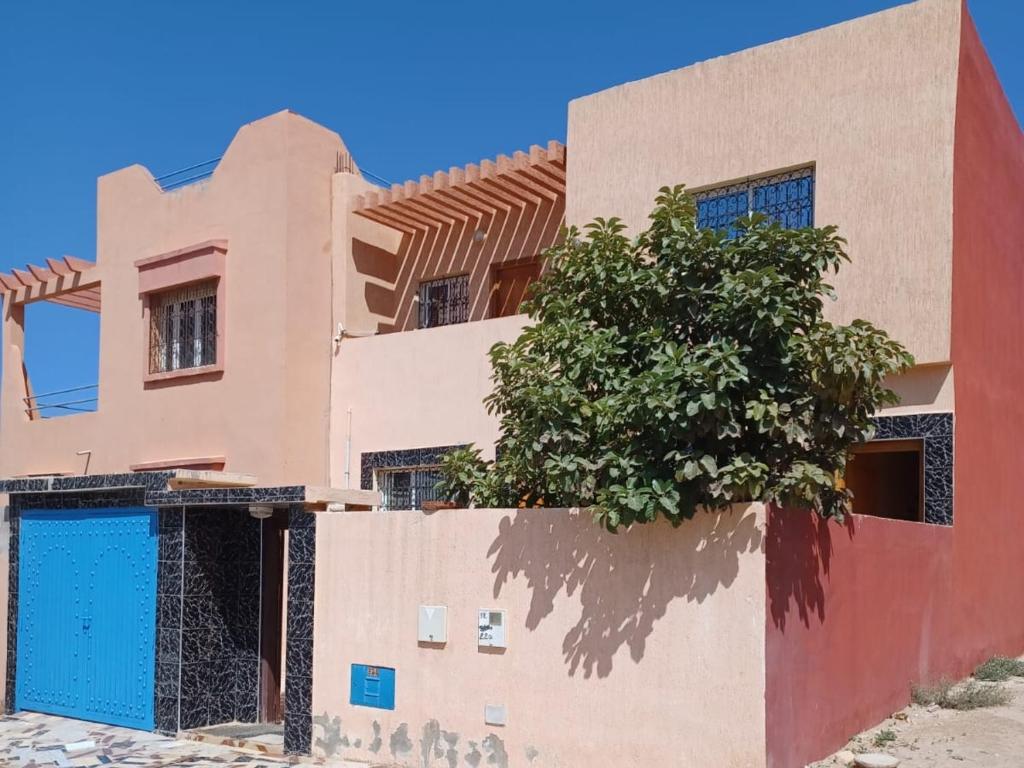 a house with a blue door and a tree at Imssouane Cathedral in Imsouane