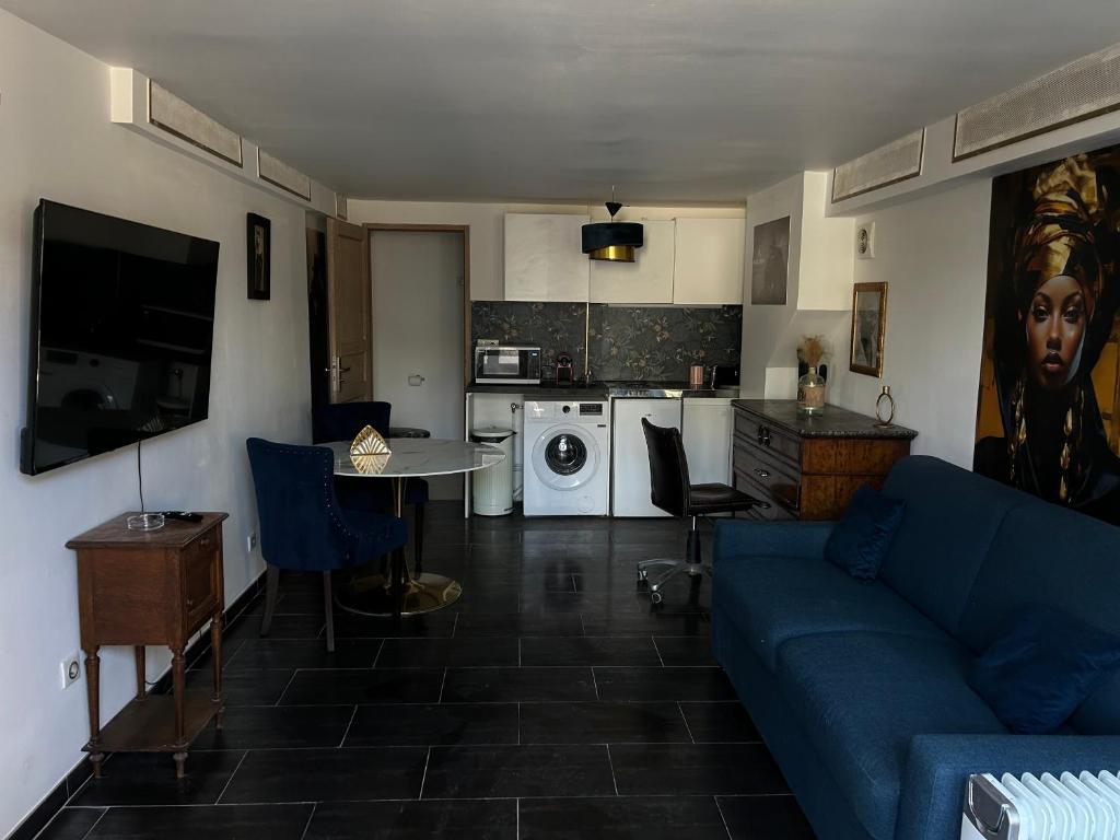 a living room with a blue couch and a kitchen at Résidence P&C Studio élégant proche Paris - Neuilly-sur-Marne in Neuilly-sur-Marne
