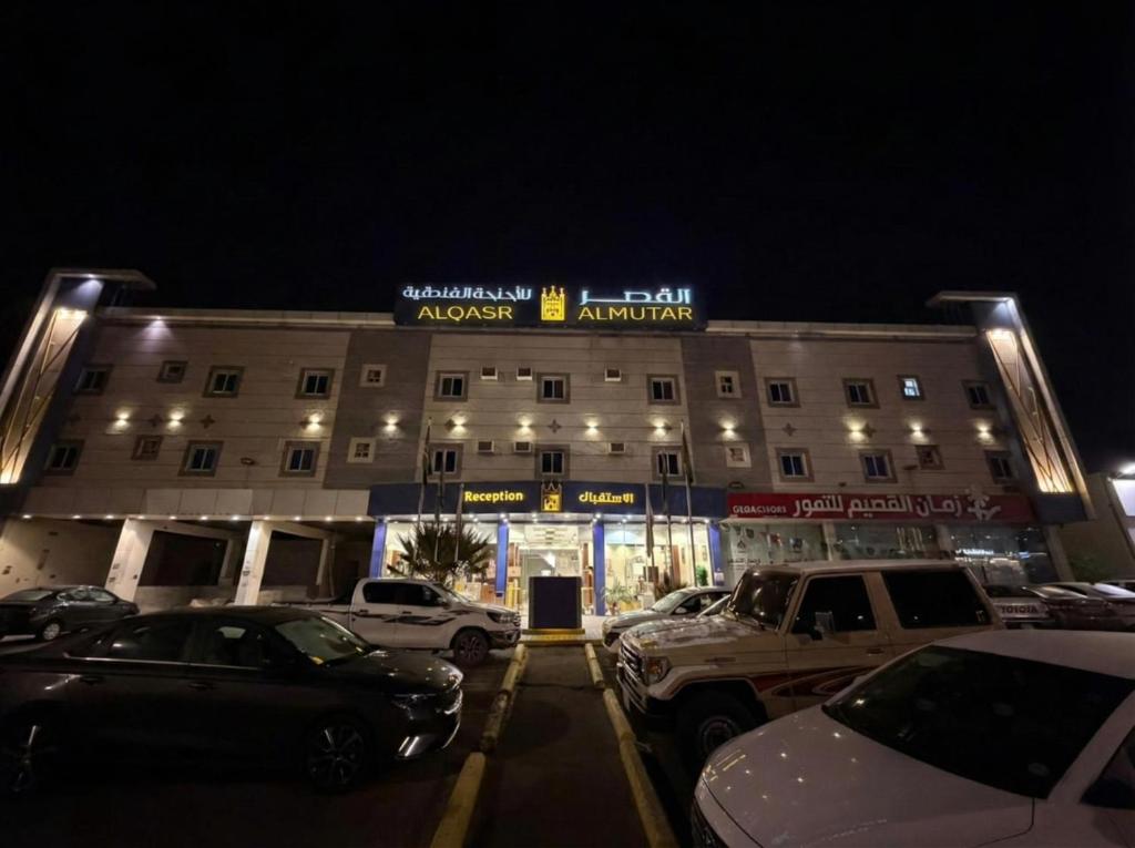 a large building with cars parked in a parking lot at Alqasr Almutar Hotel in Abha