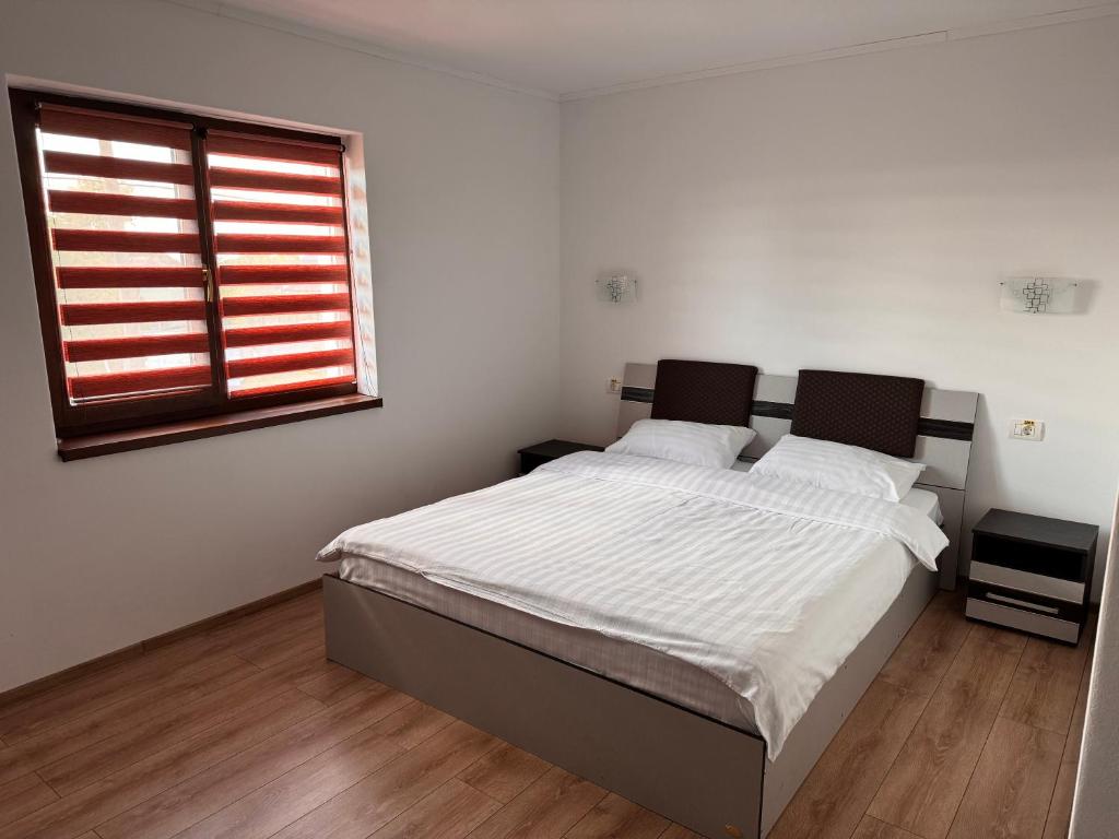a bedroom with a bed with white sheets and a window at Cazare & Restaurant Dalia in Socodor