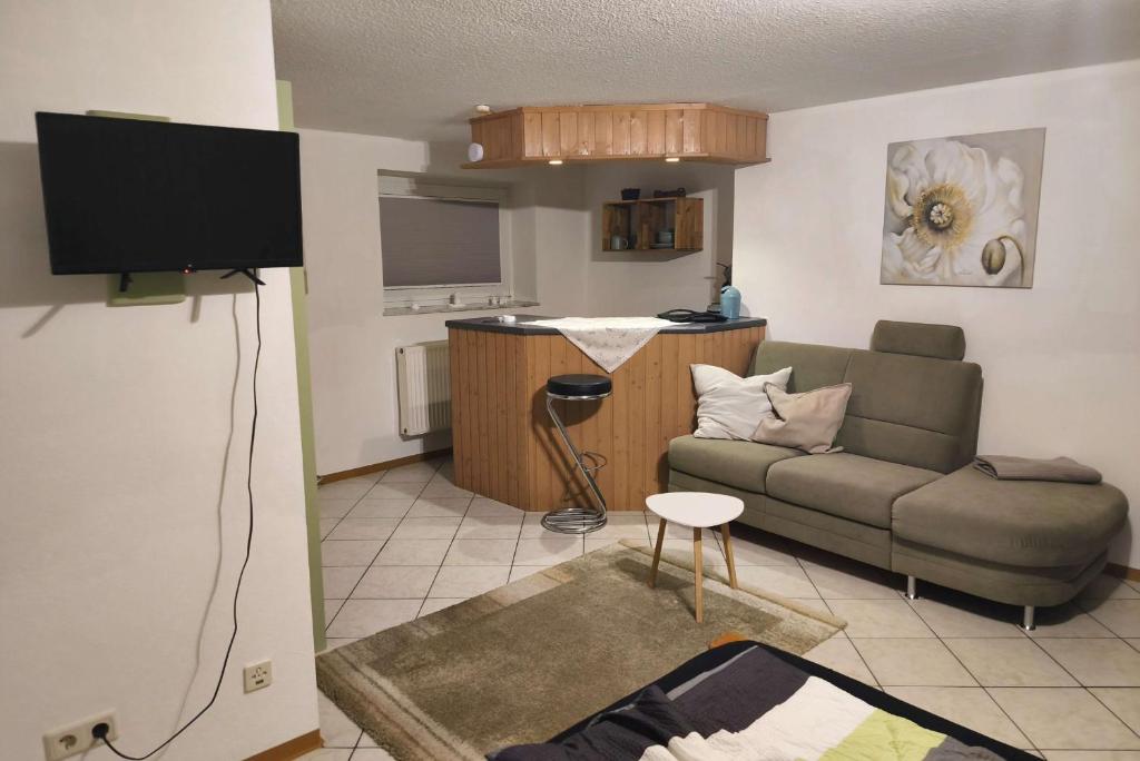 a living room with a couch and a tv at Private room with own bathroom in Harsum
