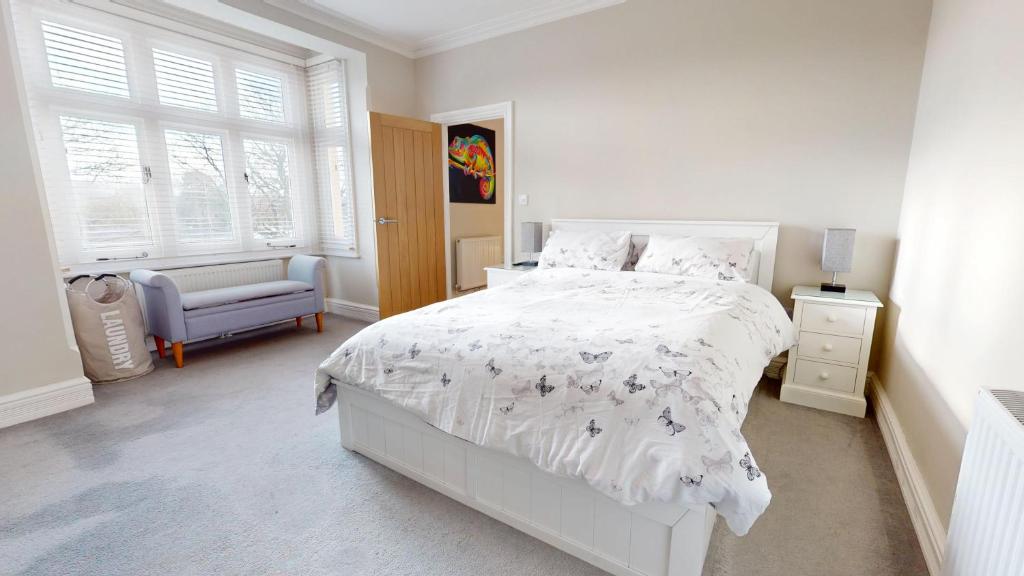 a white bedroom with a bed and a chair at Stunning 2 Bed Georgian Apartment in North Walsham