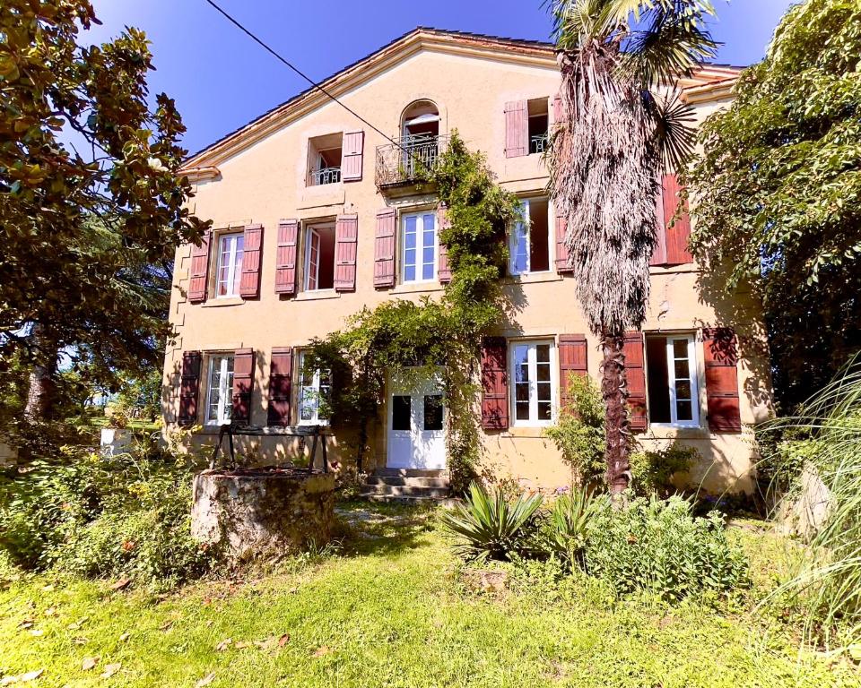 an old house with a palm tree in front of it at La Demeure des Fleurs in Caillavet