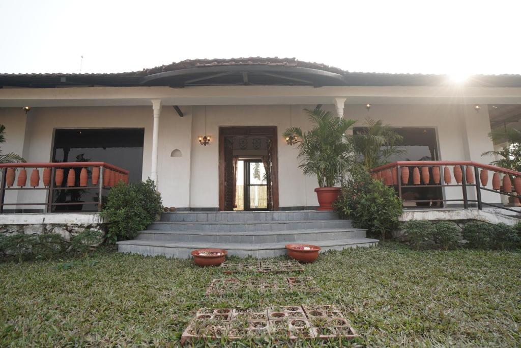 a house with a porch and stairs with plants at Mud & Meadows- A Satvik Farmstay, Jamshedpur in Jamshedpur