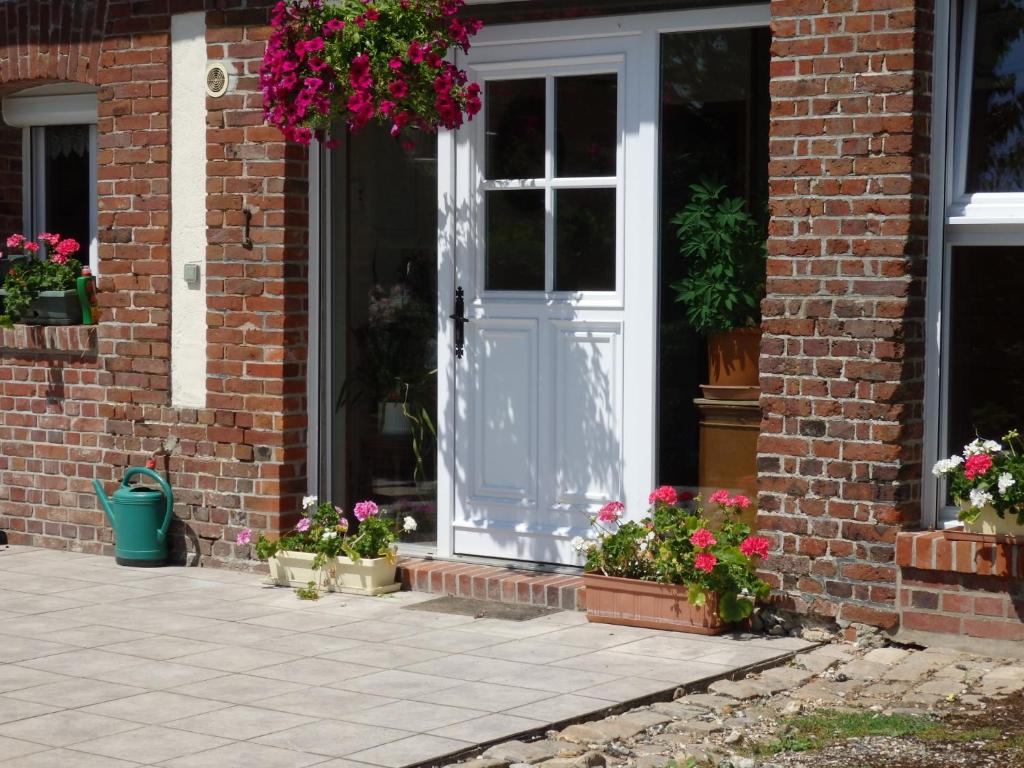 a house with a white door and some flowers at Les Trois Pommiers in Sommery