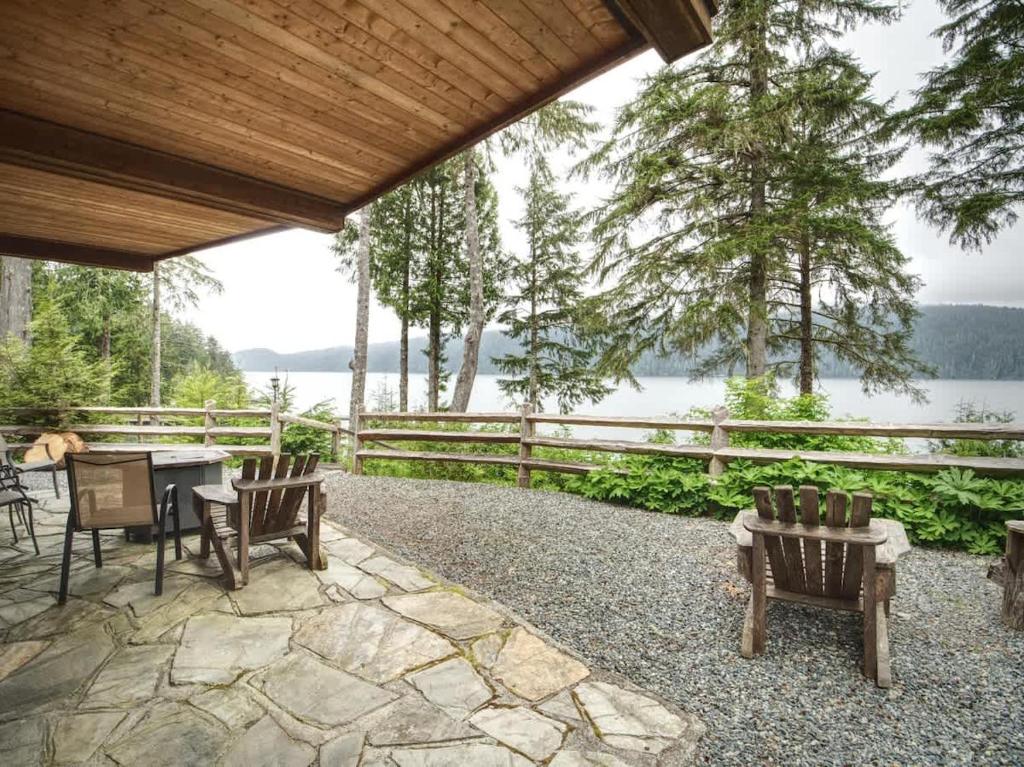 a patio with chairs and a table with a view of the water at Going Coastal ABC - Oceanfront - Pet Friendly in Port Renfrew