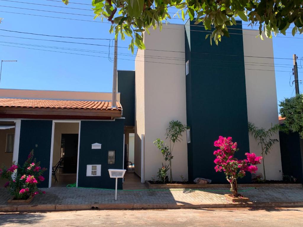 a blue and white building with pink flowers at Pousada Recanto Populina in Populina