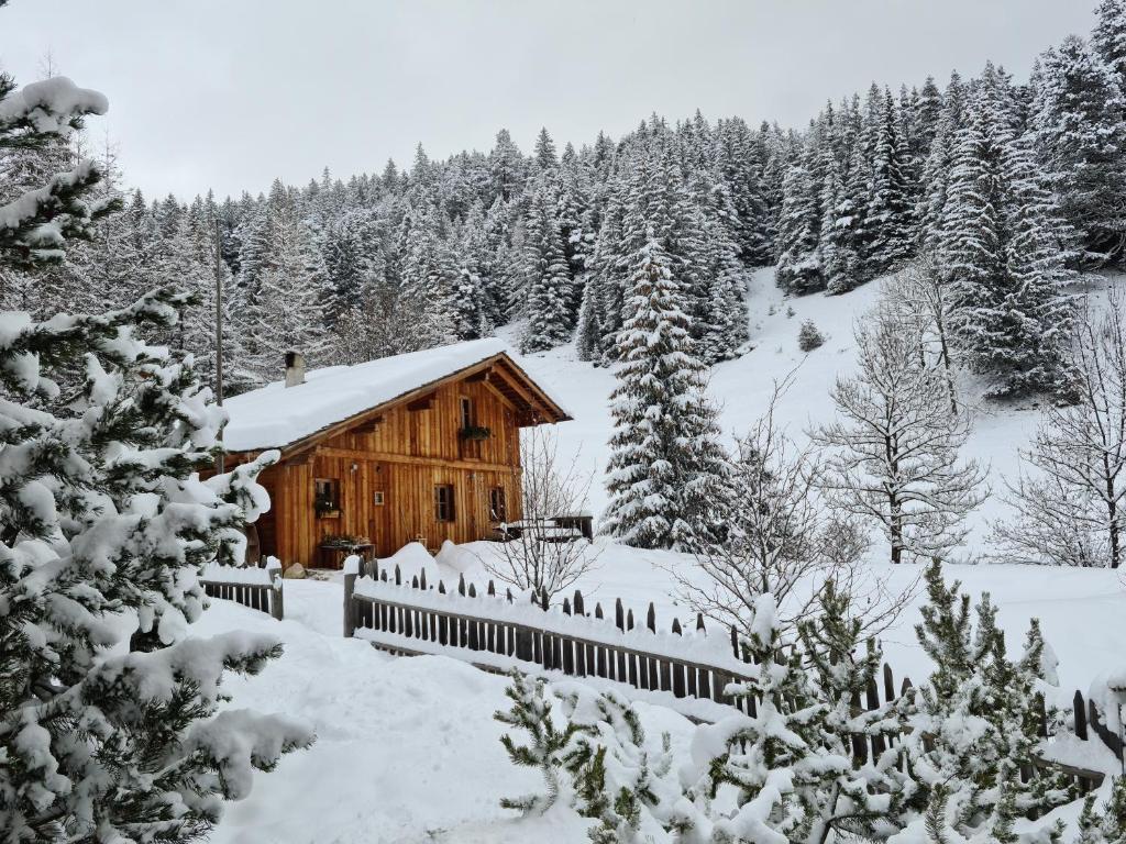 a log cabin in the snow with a fence at Molin in Vigo di Fassa