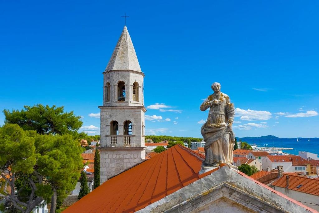 a statue on top of a building with a tower at Studio apartman Velvet in Biograd na Moru