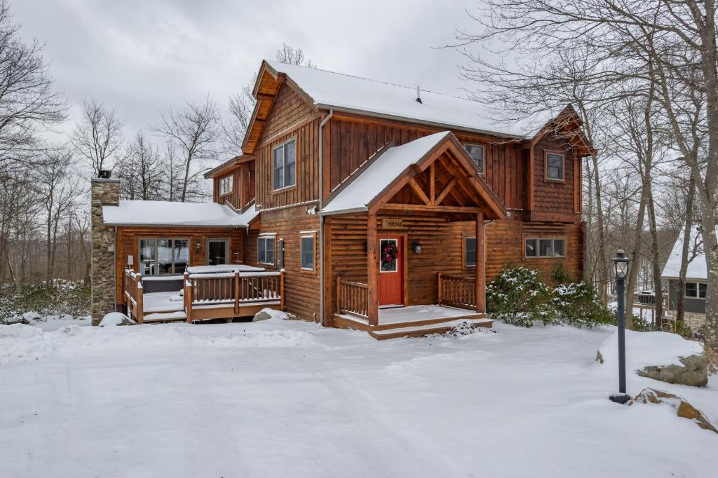 a log cabin with a red door in the snow at The Hygge Chalet by Railey Vacations in McHenry