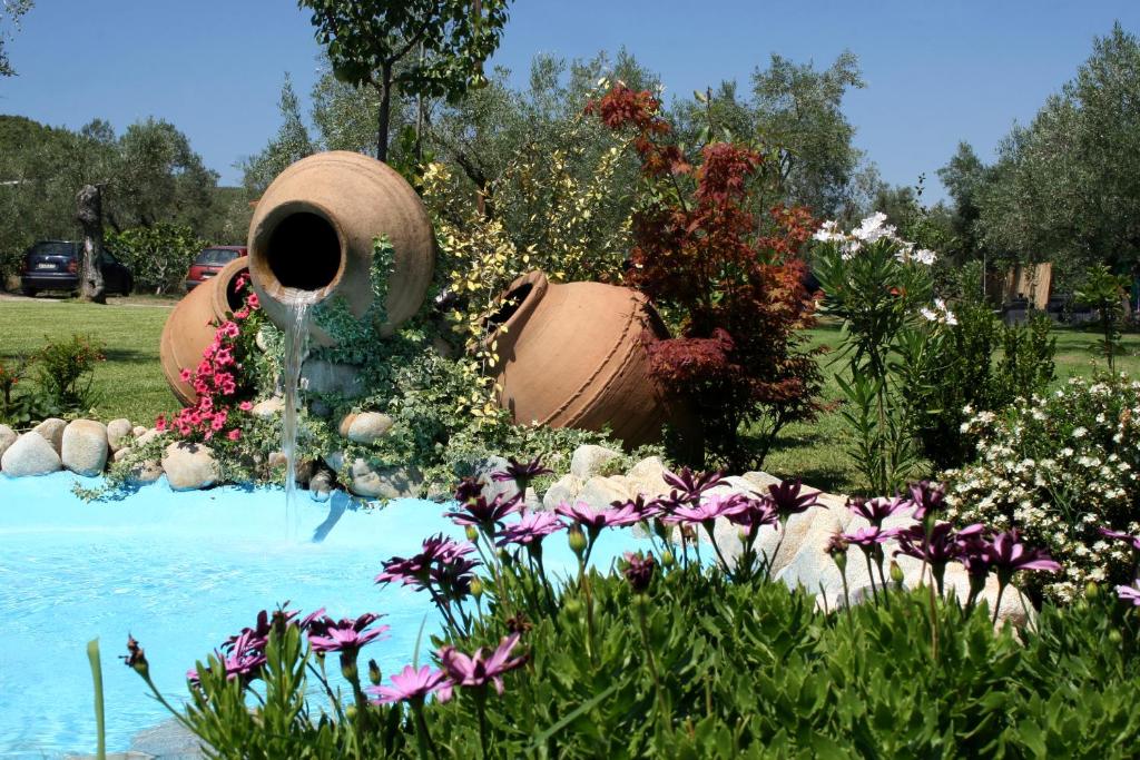 a fountain in a garden with flowers in the foreground at Ta Petrina in Vourvourou