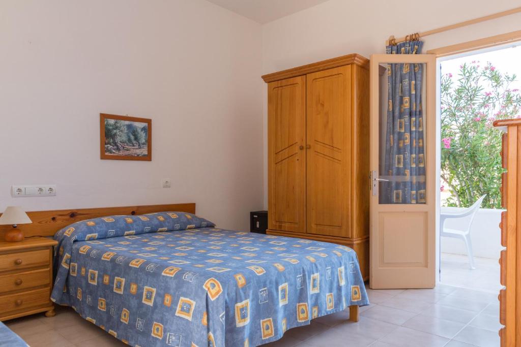 a bedroom with a bed and a cabinet and a window at Hostal Mayans in Es Pujols