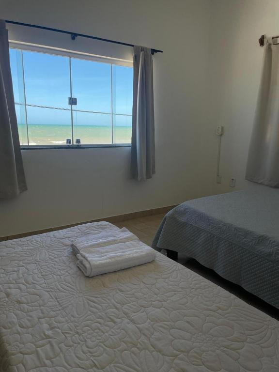 a bedroom with a bed and a window with the ocean at Pousada Sol Nascente in Mucuri