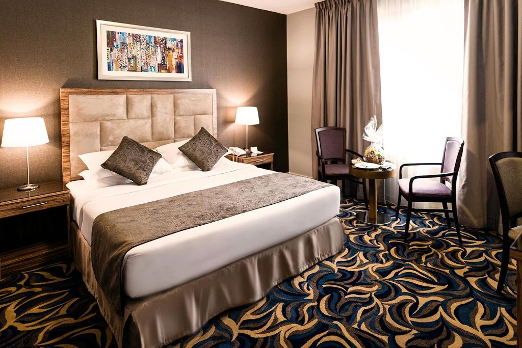 a hotel room with a bed and chairs and a window at Emirates Plaza Hotel in Abu Dhabi