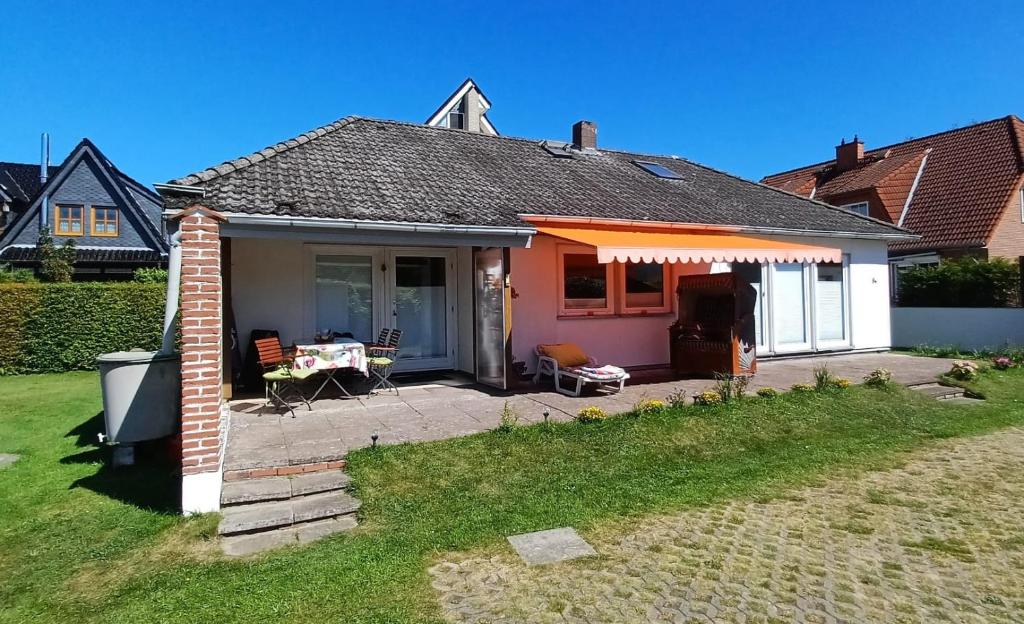 a house with a patio with a table and chairs at Ferien-Bungalow Wiesenweg in Timmendorfer Strand