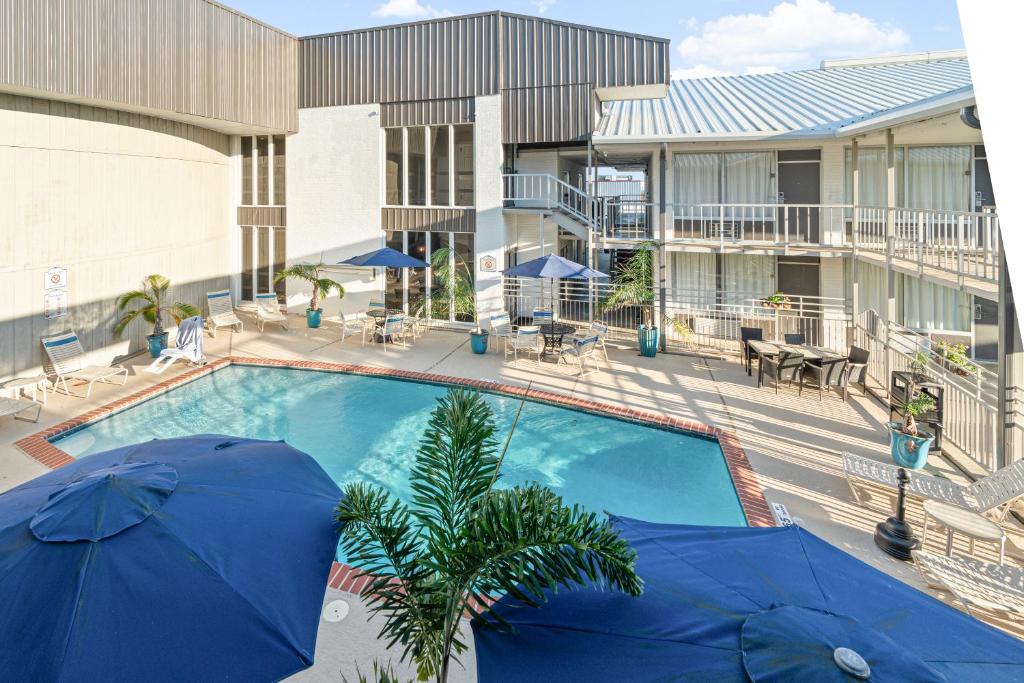 a pool with two blue umbrellas next to a building at Plantation Inn in Houma