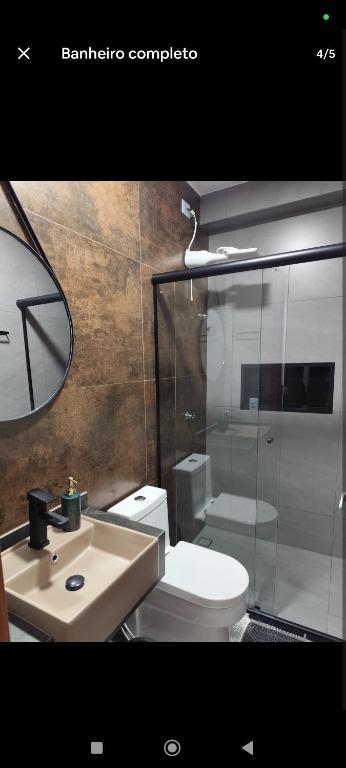 a bathroom with a toilet and a sink and a mirror at Suíte 25 vista para o mar in Pontal do Paraná