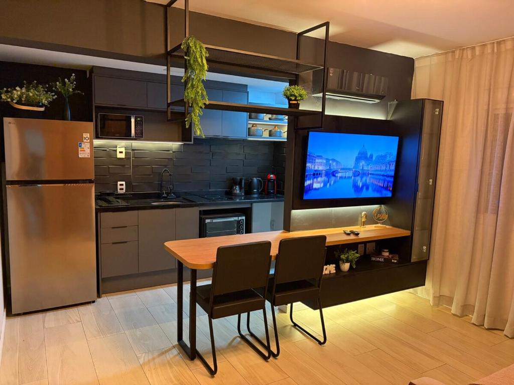 a kitchen with a table with chairs and a television at Loft completo, garagem, piscina aquecida, jacuzzi in Porto Alegre