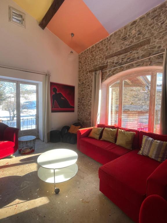 a living room with a red couch and a table at Authentic & charming dans les Monts du Lyonnais, animaux acceptés in Larajasse