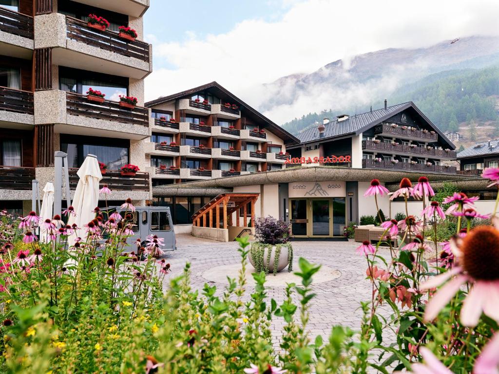 a hotel with a courtyard with flowers in front of it at Hotel Ambassador Zermatt in Zermatt