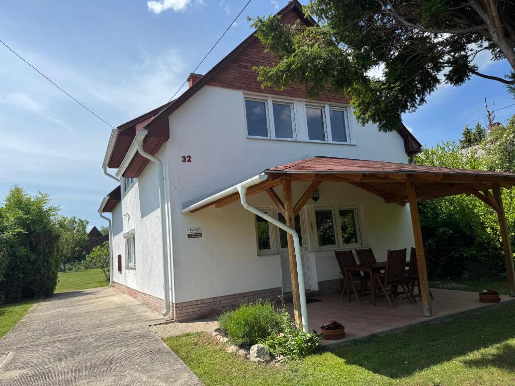 a white house with a porch and chairs at Tiszafa Apartman in Csopak