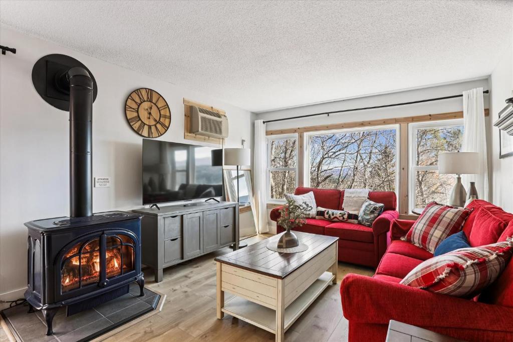 a living room with a fireplace and red furniture at The Summit at Mountainside in Stowe