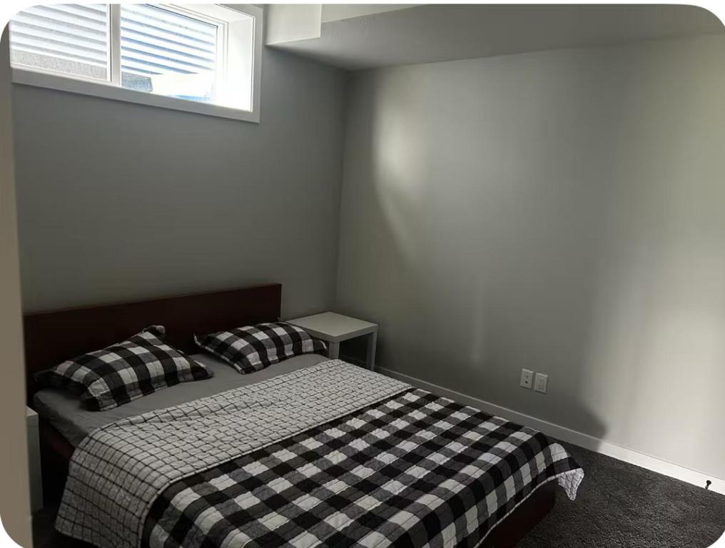 a bedroom with a black and white bed with a window at Pond view Walkout in Airdrie