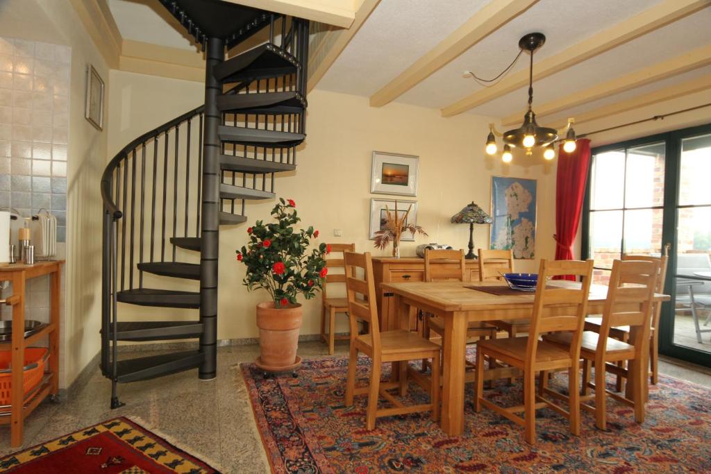 une salle à manger avec une table en bois et un escalier en colimaçon dans l'établissement Ferienwohnanlage Alte Molkerei, à Rankwitz