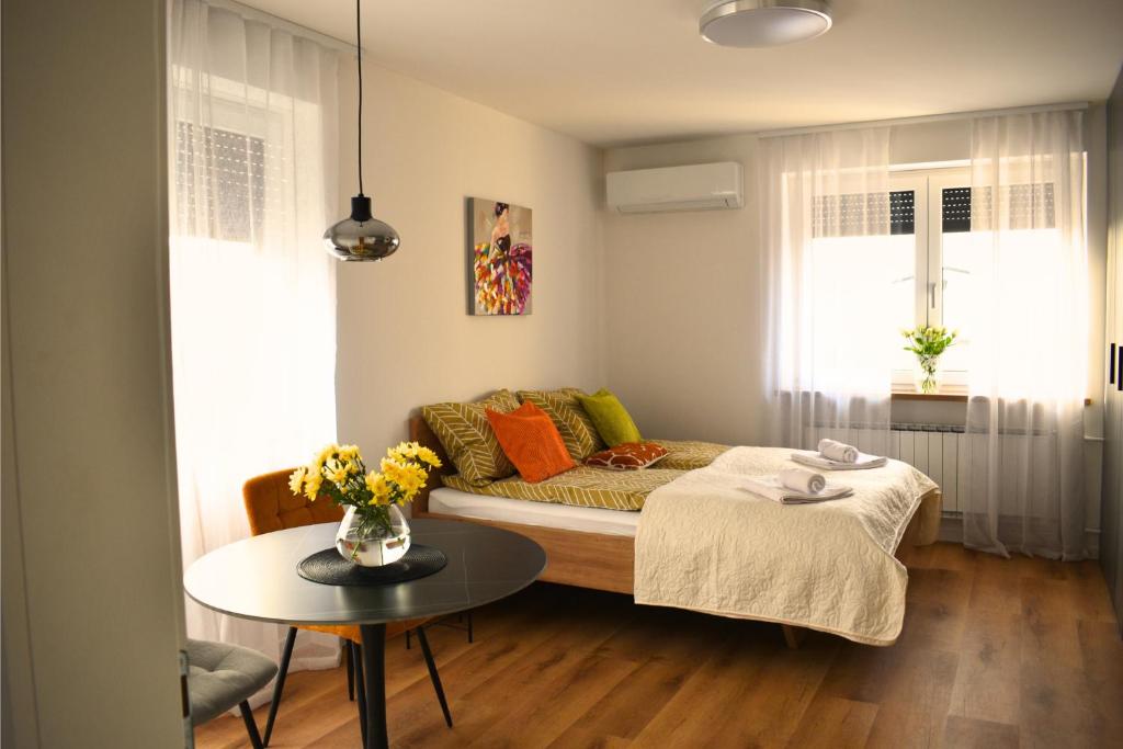 a small living room with a bed and a table at Ahat apartment- Modern stay near center & free parking in Maribor