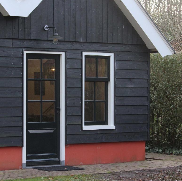 a black house with a black door and windows at Het Verborgen Jagershuisje in Wedde
